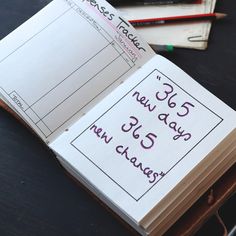 an open notebook on top of a table with pencils next to it and another notepad