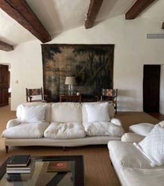 a living room filled with white furniture and a painting on the wall above it's fireplace