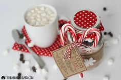 two jars with candy canes in them on a table next to spoons and peppermints