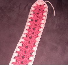 a pink and white crocheted object on a black surface