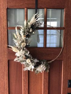 a wreath hanging on the front door of a house with frosted grass and flowers