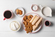 a plate with cookies, marshmallows and other treats on it next to cups of coffee