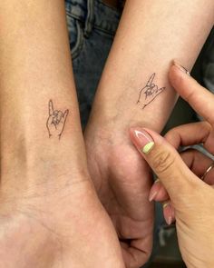 two people with matching tattoos on their arms holding each other's hands and fingers