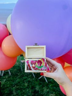 a person holding up a box in front of balloons