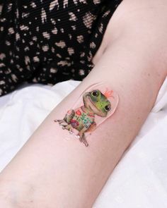 a small frog tattoo on the arm