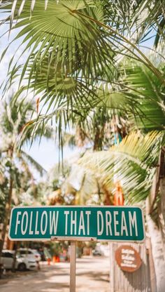 a street sign that says follow that dream in front of palm trees and parked cars