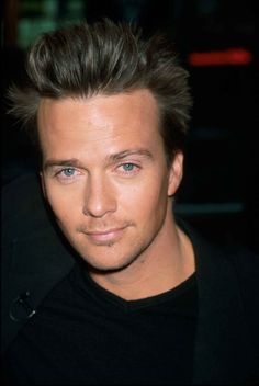 a close up of a person wearing a black shirt and looking at the camera with a serious look on his face