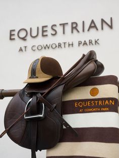 a brown and white horse saddle sitting on top of a striped blanket next to the equestrian at cowworth park sign