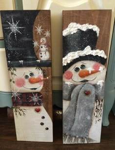 two snowmen painted on wooden boards sitting next to each other