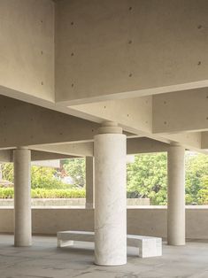 an empty room with columns and benches in the center, surrounded by concrete pillars that are lined up against each other