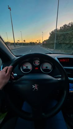 a person driving a car with the sun setting in the background