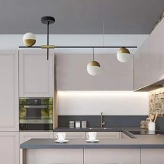 a modern kitchen with white cabinets and gray counter tops, along with stools in front of the island