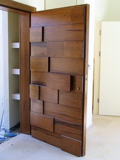 an open wooden door with several pieces of wood on the bottom and sides, in front of a white wall