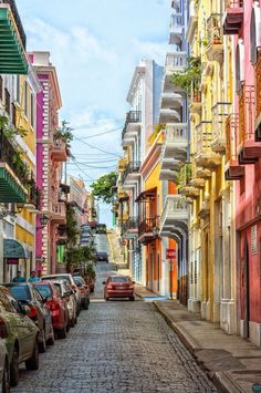 cars are parked on the street in front of multi - colored buildings