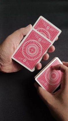 two hands holding playing cards in front of each other