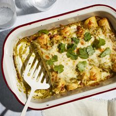 a casserole dish with green vegetables, cheese and sauce in it next to a plastic fork