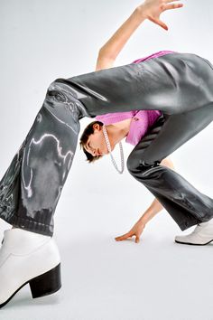 a woman in black pants and pink shirt doing a dance move with her legs spread out