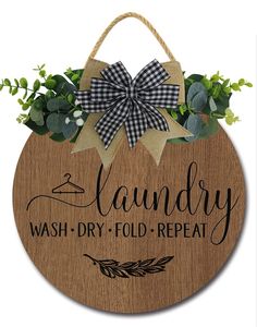 a wooden sign that says laundry, wash dry fold repeat and green leaves on it