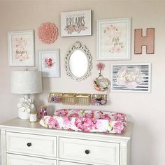 a baby's room with pink and white decor on the wall, dresser and crib