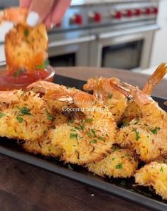 someone is dipping sauce on some food in a dish that looks like fried shrimp with parmesan cheese and herbs