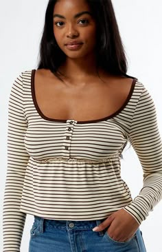 The Striped Long Sleeve Babydoll Top from Est. PAC 1980 combines classic style with a playful twist. Featuring a scoop neckline, button front placket, and a babydoll silhouette, this striped print top has a cropped length that adds a modern touch to any casual outfit.Striped print topScoop necklineLong sleevesButton front placketBabydoll silhouetteCropped lengthMachine washableModel is wearing a size smallModel measurements: 5’11” height, 35” bust, 26” waist, 38” hips Est. PAC 1980 Womens Stripe Babydoll Shirt Outfit, Clothes For Europe, Baby Doll Tops, T Aesthetic, Midi Denim Skirt, Cool Tops, Prom Birthday, Kids Activewear, Jersey Tops