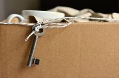 a cardboard box with a key tied to it and a cup in the middle on top