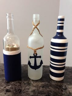 three bottles with an anchor on them are lined up next to each other and one is empty