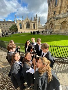 a group of young people standing next to each other in front of a building on a sunny day