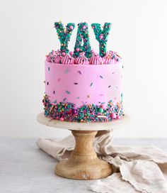 a pink birthday cake with sprinkles and the words yay on top