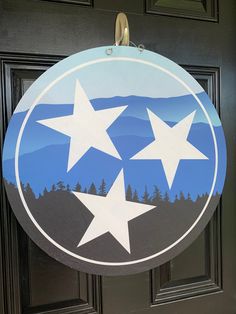 a door sign with three white stars hanging from it's side and mountains in the background