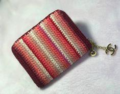 a red and white crocheted purse with a gold keychain hanging from it