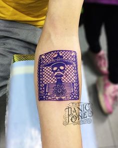 a tattoo on the arm of a person with a purple frame and skull in it