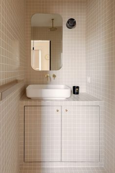 a bathroom with a sink, mirror and tiled walls in neutral colors on the wall