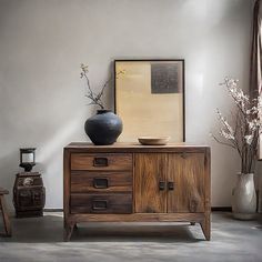 a wooden cabinet with two vases on top of it next to other furniture and decor