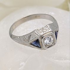 This Is A Beautiful Vintage Ring Dating Back To The Art Deco Era. Crafted In Solid 18k White Gold With An Elegant Hammered/Engraved Design, It Features Two Trilliant Cut Blue Sapphires That Flank A Gorgeous Genuine Old European Cut Diamond In The Center. This Beauty Is Estimated To Be White G Color With Vs Clarity And Weigh 1/3 Ct ( I Am Gia Certified In Diamond Grading. Weight Has Been Estimated Inside The Mounting.) Size 12 **Because This Is Over$500, It Will Go Through The Poshmark Authentica Sapphire Art Deco Ring, Art Deco Rings, Beautiful Rings Vintage, Engraved Design, I Am Gia, European Cut Diamonds, Art Deco Era, Art Deco Ring, Vintage Ring