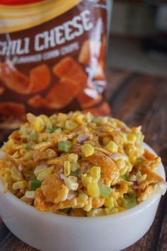 a bowl filled with corn kernels next to a bag of chips