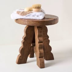 a wooden stool with a white towel on top of it and a hair brush sitting on top of it