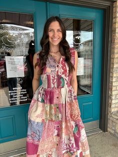 a woman standing in front of a blue door wearing a dress made out of fabric