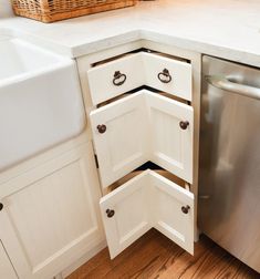 a kitchen with white cabinets and an open dishwasher drawer in the corner next to a sink