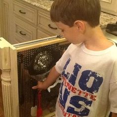 a young boy standing in front of a kitchen sink opening the door to his new dishwasher