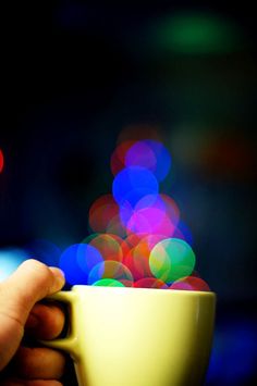 a person holding a coffee cup with blurry lights in the backgroung