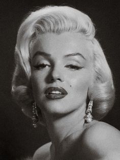 a black and white photo of a woman with blonde hair wearing large earrings, looking off to the side