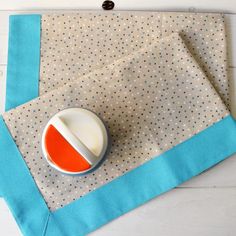 an orange and white bowl sitting on top of a piece of cloth next to a button