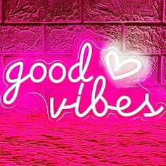 a neon sign that says good vibes in front of a brick wall with a heart