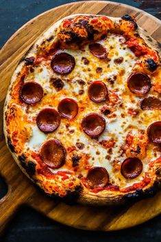 a pepperoni pizza sitting on top of a wooden cutting board