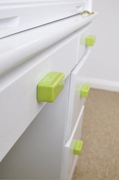 a white dresser with green knobs on it