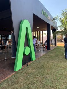 people are sitting at tables in front of a building with an ad on the side