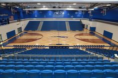 an empty basketball court with blue seats