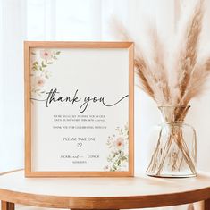 a thank you card next to a vase filled with dried grass and pamy flowers