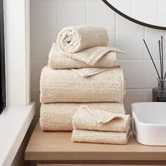 a stack of towels sitting on top of a wooden counter next to a white bowl